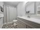 Well-lit bathroom features a gray vanity, updated faucet, and patterned black and white tile floor at 605 W Holt St, Mebane, NC 27302