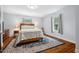 Bright bedroom features a floral comforter, two windows, wood floors, and an oriental rug at 605 W Holt St, Mebane, NC 27302