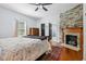 Bedroom featuring hardwood floors, stone fireplace, ceiling fan, and ensuite bathroom at 605 W Holt St, Mebane, NC 27302