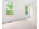 A bright, carpeted bedroom with two windows offering natural light and views of the surrounding greenery at 619 Baybush Dr, Raleigh, NC 27615
