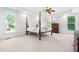 A serene main bedroom featuring a four-poster bed, tray ceiling, and ample natural light from large windows at 619 Baybush Dr, Raleigh, NC 27615