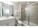 Well-lit bathroom featuring a glass-enclosed shower, white vanity, and neutral tile at 7809 Lillyhurst Dr, Raleigh, NC 27612