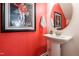 Charming half-bath featuring a pedestal sink, red accent wall and vintage artwork at 7809 Lillyhurst Dr, Raleigh, NC 27612