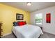 Cozy bedroom featuring bright yellow accent wall, window, queen size bed, and colorful artwork at 7809 Lillyhurst Dr, Raleigh, NC 27612