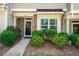 Charming townhome entrance with a decorative wreath, lush landscaping, and a welcoming walkway at 7809 Lillyhurst Dr, Raleigh, NC 27612