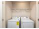 Functional laundry area with washer, dryer, and overhead storage shelving at 7809 Lillyhurst Dr, Raleigh, NC 27612