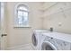 Bright laundry room with white washer and dryer, window, and shelving for storage at 808 Historian St, Raleigh, NC 27603