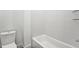 Clean white tiled bathroom features a built-in tub and toilet at 810 Culpepper Ln, Raleigh, NC 27610