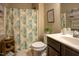 Neutral bathroom with a floral shower curtain, dark cabinets, and a plant at 90 Weatherly Dr, Franklinton, NC 27525