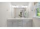 Bathroom vanity with double sinks, gold hardware, a large mirror, and lots of natural light at 907 Lake Beacon Way, Raleigh, NC 27606