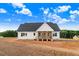 View of home's rear exterior showing its covered wood porch and white siding under a blue sky at 9427 Turkey Way, Middlesex, NC 27557