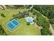 Aerial view of the community pool, tennis courts, and playground surrounded by lush greenery and parking at 1008 Old Meetinghouse Way, Raleigh, NC 27615