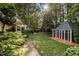 Manicured backyard featuring a gazebo, pergola, and lush landscaping, creating a tranquil outdoor oasis at 102 Alidade Ct, Cary, NC 27513