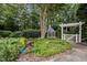 Landscaped garden with flowers, stone retaining wall, and a gazebo with a white pergola, set in a lush green environment at 102 Alidade Ct, Cary, NC 27513