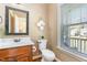 Charming half bathroom with vanity, toilet, decorative mirror and natural light from the window at 114 Boone Trl, Garner, NC 27529
