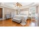 Cozy main bedroom featuring hardwood floors, a tray ceiling, a ceiling fan, neutral colors, and two windows for natural light at 114 Boone Trl, Garner, NC 27529