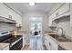 Updated kitchen boasts stainless steel appliances, white cabinets, and granite countertops with dining room view at 1221 Teakwood Pl, Raleigh, NC 27606