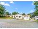 Rear view of home with white siding, small patio, and gravel driveway and yard at 1315 Elder Way, Burlington, NC 27215