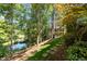 Scenic backyard with mature trees, a pond, and a stepping stone pathway through the grass at 145 Cofield Cir, Durham, NC 27707