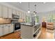 Open concept kitchen with island, breakfast bar, stainless appliances, and easy access to the living area at 145 Cofield Cir, Durham, NC 27707