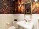Charming powder room featuring floral wallpaper, ornate mirror, pedestal sink, and classic fixtures at 1512 St. Mary'S St, Raleigh, NC 27608