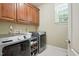 Laundry room with modern washer and dryer and wooden storage cabinets at 164 Avocet Ln, Clayton, NC 27520