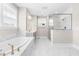 Bright bathroom featuring marble tile, a soaking tub, vanity, and a glass-enclosed shower at 2720 Spotted Coral Ct, Apex, NC 27502