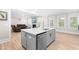 Open concept kitchen with gray island, stainless dishwasher, and view into the living room with a fireplace at 2720 Spotted Coral Ct, Apex, NC 27502