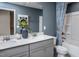 Well-lit bathroom with double vanity, quartz countertop, and tub with stylish blue patterned shower curtain at 273 Broomside Ave, Raleigh, NC 27603