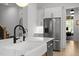 Bright kitchen with a stainless steel refrigerator, white cabinets, marble counters, and a matte black faucet at 3057 Eden Harbor Ct, Raleigh, NC 27613