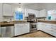 Well-lit kitchen featuring white cabinetry, granite countertops, and stainless steel appliances at 311 Westbrook Dr, Carrboro, NC 27510