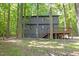 Back exterior view of the two-story house with wood siding and a deck surrounded by green trees at 3218 Seven Springs Rd, Hillsborough, NC 27278