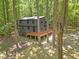 Rear exterior view of a home with a wooden deck surrounded by a lush, wooded landscape providing privacy at 3218 Seven Springs Rd, Hillsborough, NC 27278