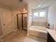 Bathroom featuring tiled floors, a glass shower, and a soaking tub beneath a window at 3509 Bailey Lake Dr, Fuquay Varina, NC 27526