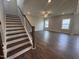 Bright living room with dark floors, a staircase, and large windows, perfect for gathering or relaxing at 3509 Bailey Lake Dr, Fuquay Varina, NC 27526