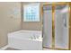Bathroom featuring a large soaking tub, glass block window, and separate shower stall at 5107 Granbury Dr, Durham, NC 27713
