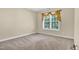 Bedroom with neutral walls and carpet features a window with decorative curtains at 5107 Granbury Dr, Durham, NC 27713