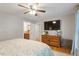 Bright bedroom with hardwood floors, ceiling fan, large TV, and access to the ensuite bathroom at 5908 Danville Dr, Raleigh, NC 27612