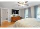 Spacious bedroom features hardwood floors, ceiling fan, natural light, and dresser with mounted television at 5908 Danville Dr, Raleigh, NC 27612