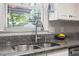 Close-up of kitchen sink with stainless steel faucet, granite countertops, and natural light from the window at 5908 Danville Dr, Raleigh, NC 27612