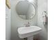Stylish powder room with a pedestal sink, decorative mirror, and soft lighting at 5908 Danville Dr, Raleigh, NC 27612