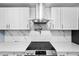 This updated kitchen features white cabinets, quartz counters and backsplash, and a stainless vent hood at 6005 Lake Wheeler Rd, Raleigh, NC 27603