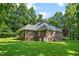 Rear view of a red brick home surrounded by a sprawling green lawn and mature trees, creating a private setting at 745 Oaks Lane Rd, Timberlake, NC 27583