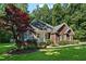 Red brick home featuring a lush, green lawn, a vibrant red tree, and a welcoming covered porch at 745 Oaks Lane Rd, Timberlake, NC 27583