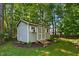 Well-maintained storage shed in a wooded backyard, featuring double doors and a ramp for easy access at 745 Oaks Lane Rd, Timberlake, NC 27583