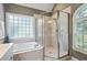 Modern bathroom with tiled shower, soaking tub, and large windows at 7801 Kingsbrook Ct, Wake Forest, NC 27587