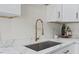 Close-up of a kitchen sink with modern fixtures, white countertops and white cabinets at 813 N Main St, Burlington, NC 27217