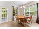 Sunlit dining area featuring a classic chandelier and views of the fenced backyard through large windows and a glass door at 822 Blue Lake Dr, Mebane, NC 27302