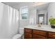 Bright bathroom with white walls, wooden cabinets, a shower with a white curtain, and a window at 93 Kinsale Ct, Garner, NC 27529