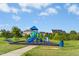 Community playground with blue, green, and yellow play structures set in a grassy park area with a blue sky at 93 Kinsale Ct, Garner, NC 27529